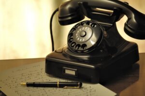 old fashioned telephone and fountain pen photographed in sepia tone.